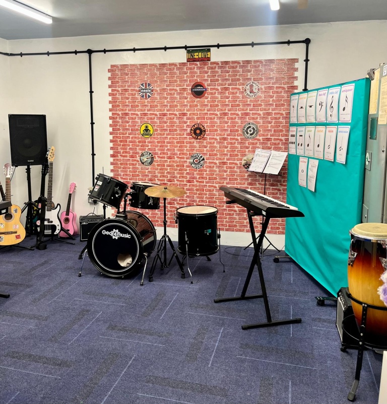 The ARC music room, with drum kit, keyboard and brick feature wall