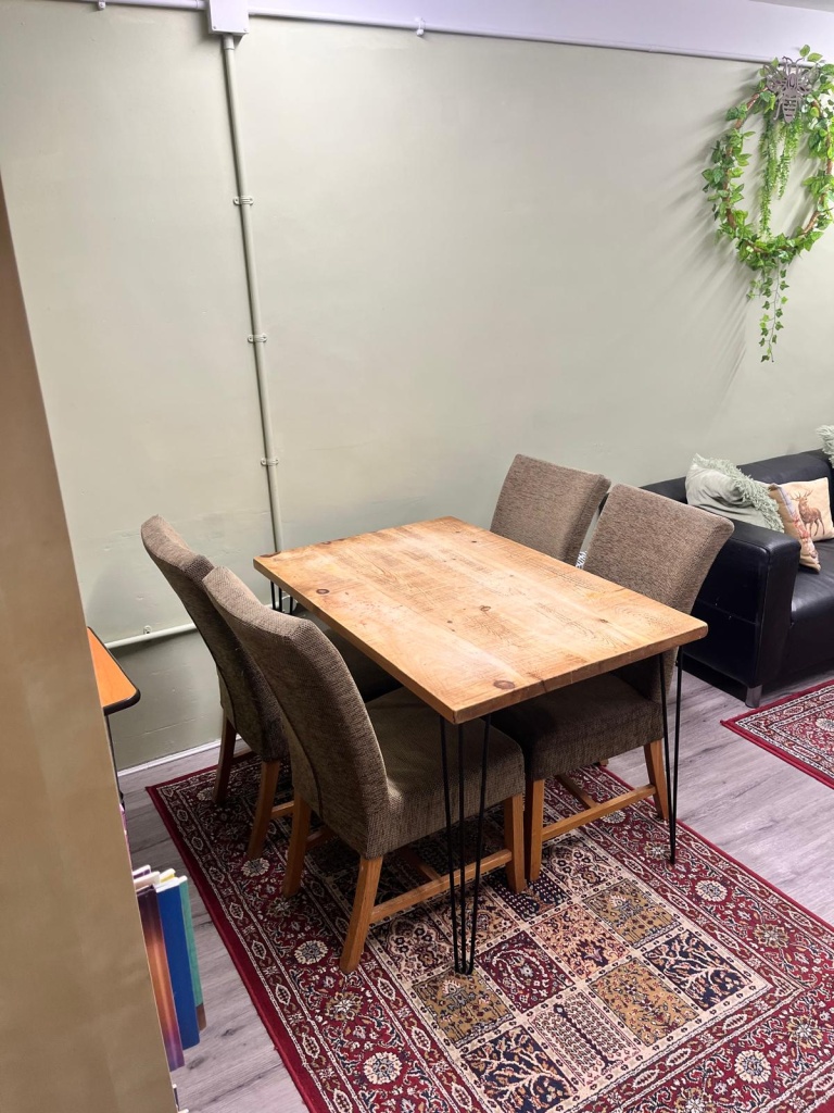 A reclaimed wood dining table and four chairs in The ARC 1 Snug, beside the seating area